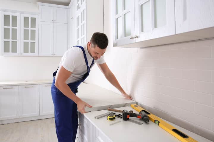 A contractor installs new countertops in a kitchen.